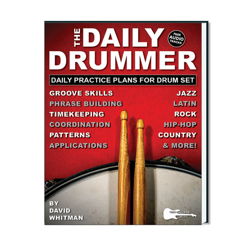 Image of a drum with 2 drum sticks resting on top on a book cover
