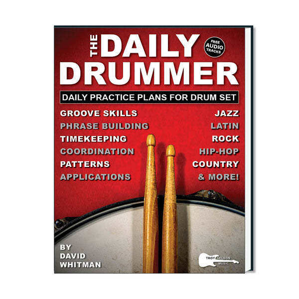 Image of a drum with 2 drum sticks resting on top on a book cover
